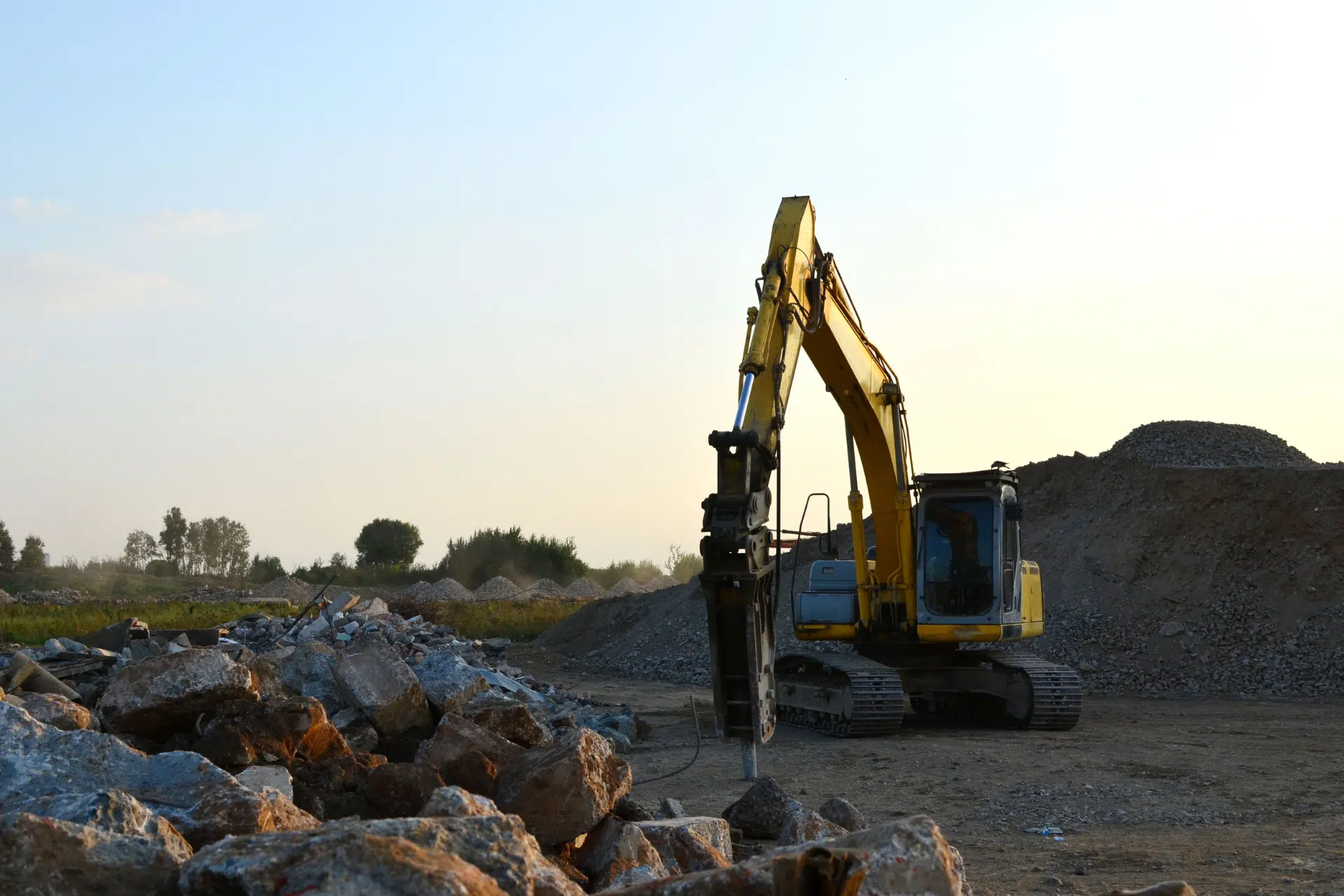 Hydraulic breaker digging in the ground at construction site.