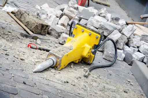 a yellow hydraulic tool in front of a lot of bricks